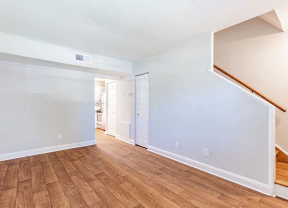 the living room and dining room of an empty house with wood flooring