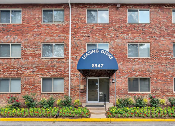 a brick building with a blue awning and the words leasing office on it