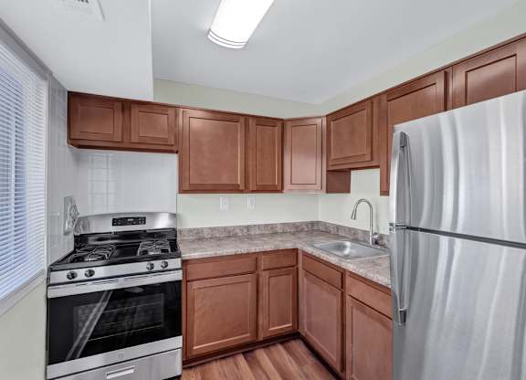 A kitchen with brown cabinets and a stainless steel refrigerator.