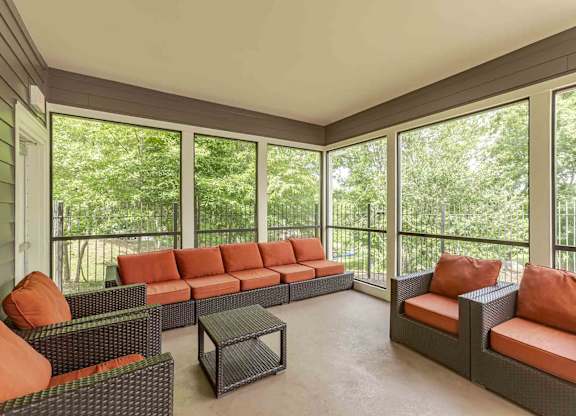 A sunroom with a couch, chairs, and a coffee table.