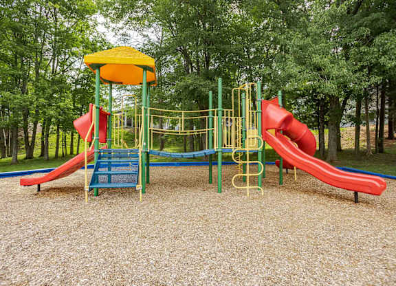 A playground with a red slide and a yellow canopy.