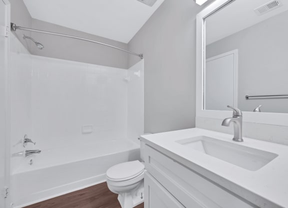 A minimalist white bathroom, complete with a sink, toilet, and shower, epitomizing elegance and functionality.