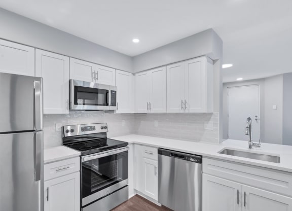 Immaculate kitchen featuring sleek stainless steel appliances and pristine white cabinets.
