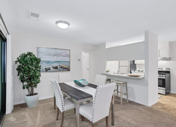 a dining area with a table and chairs and a kitchen in the background