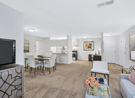 a living room and dining area with a television and kitchen in the background