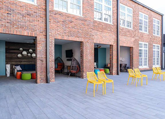 a patio with yellow chairs in front of a brick building