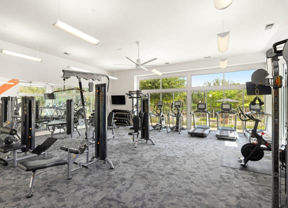 a gym with weights and cardio equipment in a building with large windows