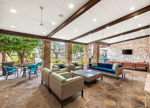 an outdoor living room with couches and chairs and a tv