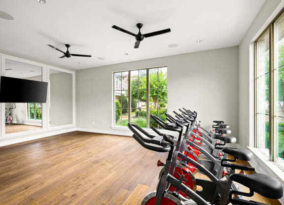 the home gym has a wall of windows and a row of exercise bikes