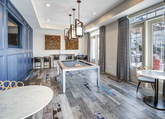 A room with a pool table and a dining table.