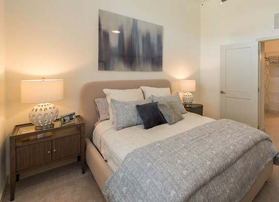 A bedroom with a large bed and a painting on the wall.
