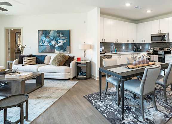 A modern kitchen and living room with a dining table and chairs.