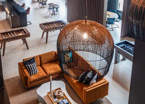 a room with a large bird cage hanging from the ceiling and a lobby with furniture