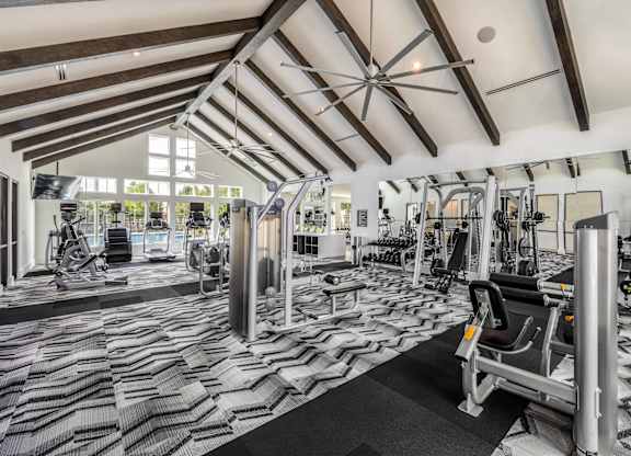 A gym with a variety of equipment including treadmills, weights, and exercise machines.
