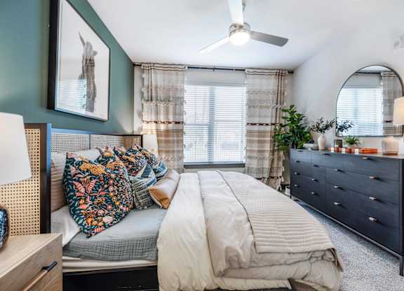 A bedroom with a bed, dresser, and a ceiling fan.