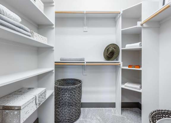 A small, white, and clean room with a bed, a chair, and a trash can.