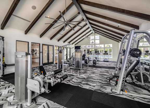 A gym with a variety of equipment including a treadmill, weights, and a bench press.