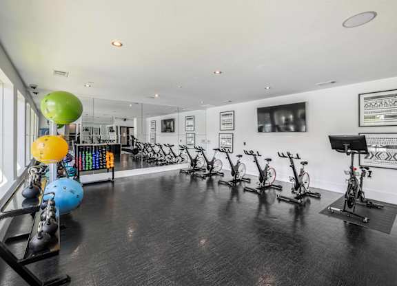 A gym with exercise equipment and a wall of pictures.