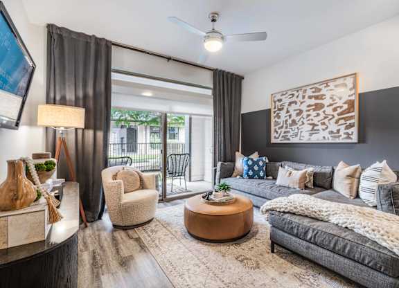 A modern living room with a grey couch, a coffee table, and a large painting on the wall.