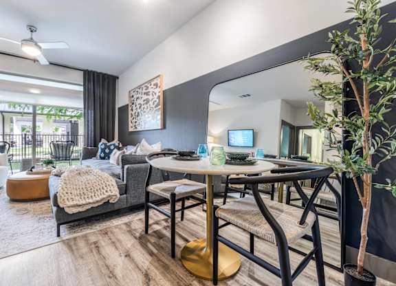 A modern living room with a grey couch, a wooden coffee table, and a TV on the wall.
