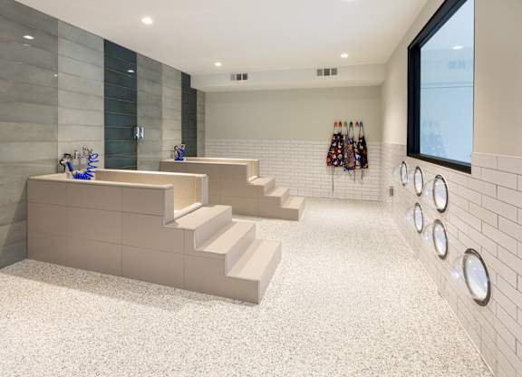 a set of stairs in a gym with white tile walls and a row of weights
