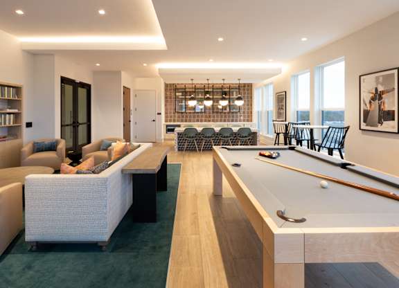 a living room with a pool table and a dining room