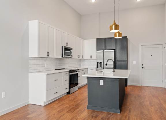 A kitchen with a black island and white cabinets.