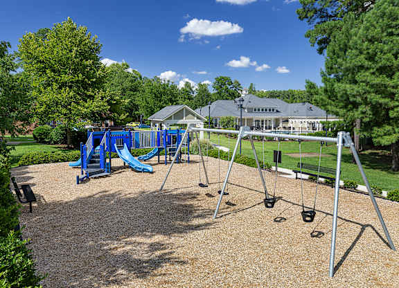 A playground with a blue slide and swings.