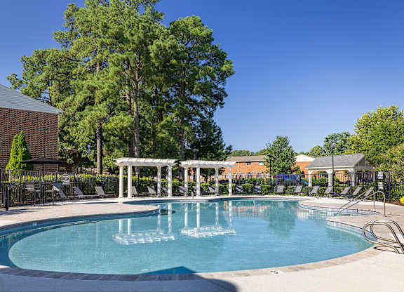 A large swimming pool surrounded by trees and lounge chairs.