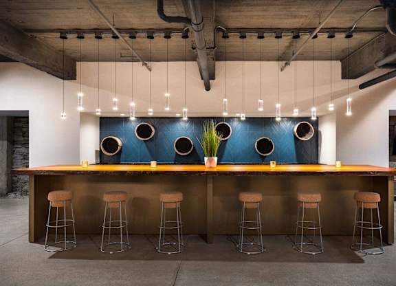 a bar with stools in front of a blue wall with pendant lights