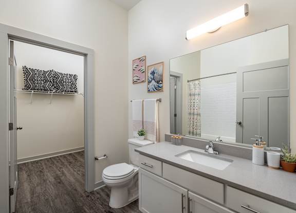 A bathroom with a toilet, sink, and mirror.