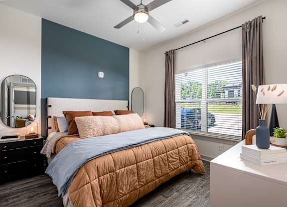 A bedroom with a bed, nightstand, and window.