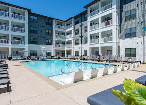 A large swimming pool in front of apartment buildings.