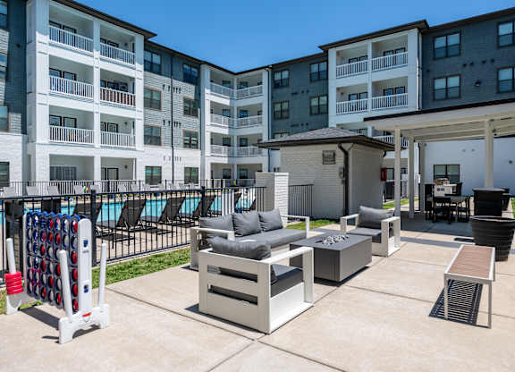 A patio area with a table, chairs, and a pool in the background.