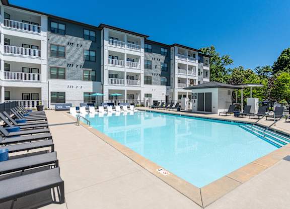 A large swimming pool in front of a multi-story apartment building.