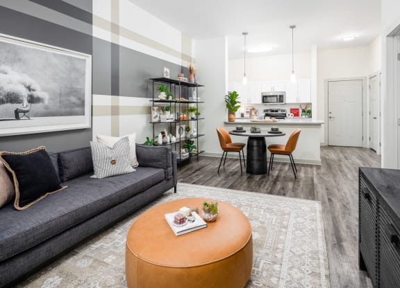 a living room with a couch a table and chairs and a kitchen in the background