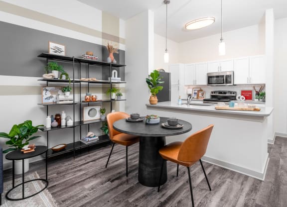 a dining area with a table and chairs and a kitchen in the background