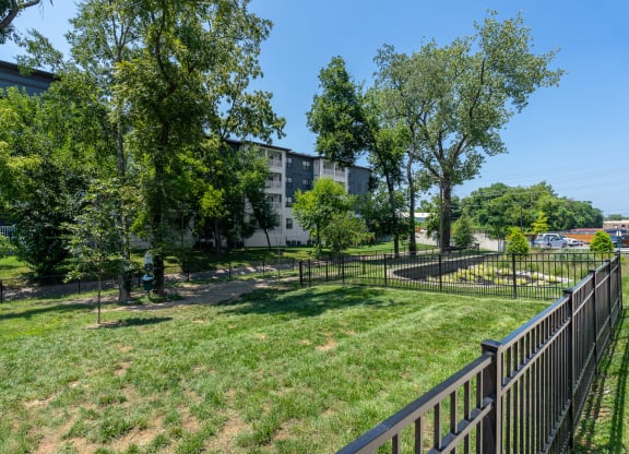 a grassy area with trees and a fence in front of a building