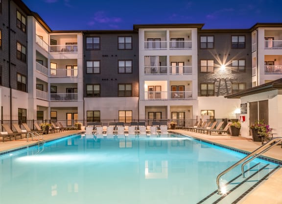 a swimming pool with chaise lounge chairs and a building in the background