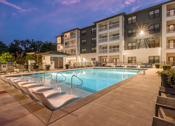 a swimming pool with chaise lounge chairs and a building in the background
