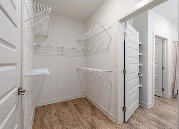 A white closet with shelves and a wooden floor.
