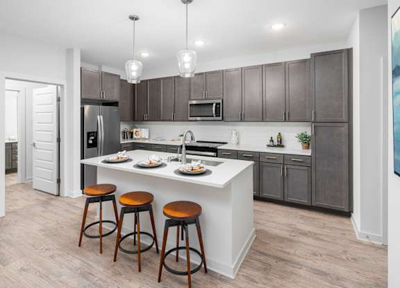 A kitchen with a white island and brown bar stools.