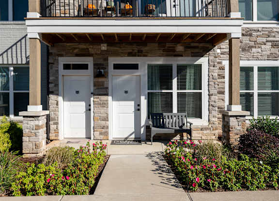 A house with a white door and windows with a bench in front.
