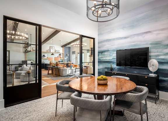 A modern dining room with a wooden table and grey chairs.