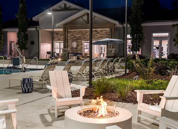 A fire pit sits in the middle of a patio surrounded by chairs.