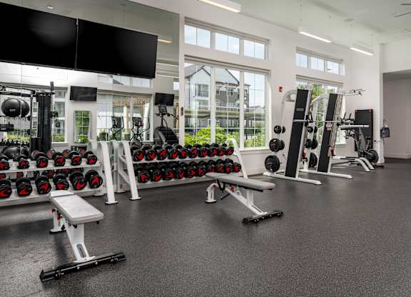 A gym with a variety of equipment including dumbbells, weight machines, and benches.