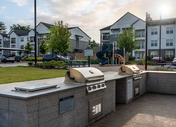 A sunny day at a residential complex with a bbq grill in the foreground.