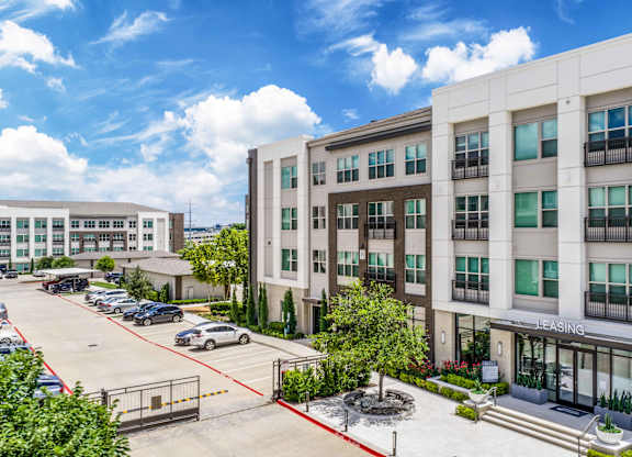 A parking lot in front of a multi-story building with a sign that says "Leasing.".