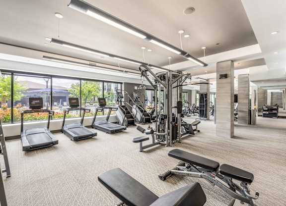 A spacious gym with a variety of equipment and a view of the outdoors.