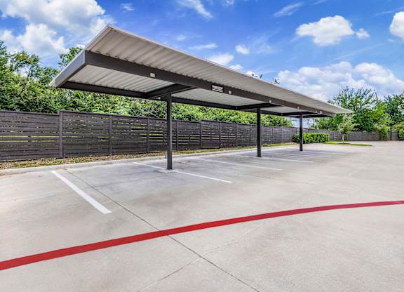 A parking lot with a canopy and red lines on the ground.
